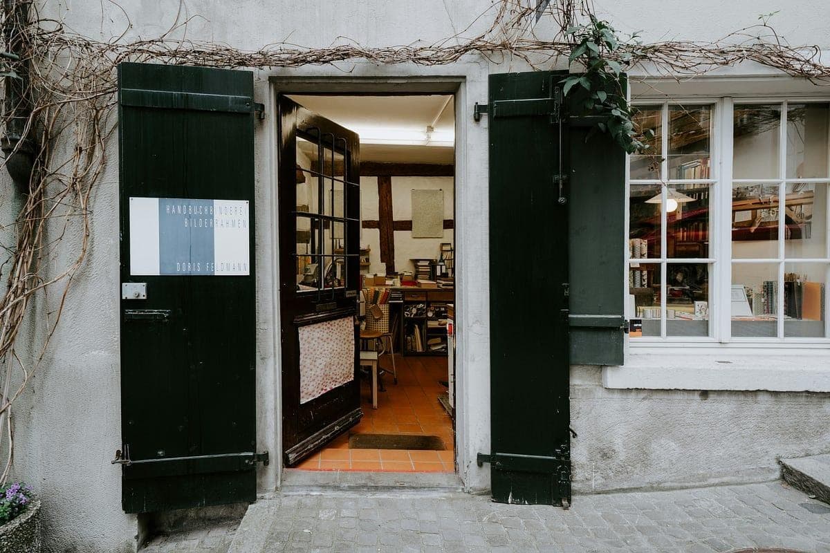 The open door of a small bookbindery, with dark green shutters and a workshop visible inside